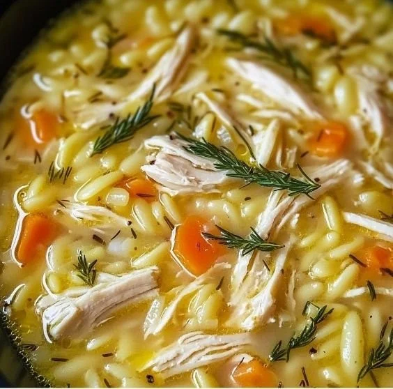 Bowl of Greek Lemon Chicken Soup garnished with lemon and herbs.
