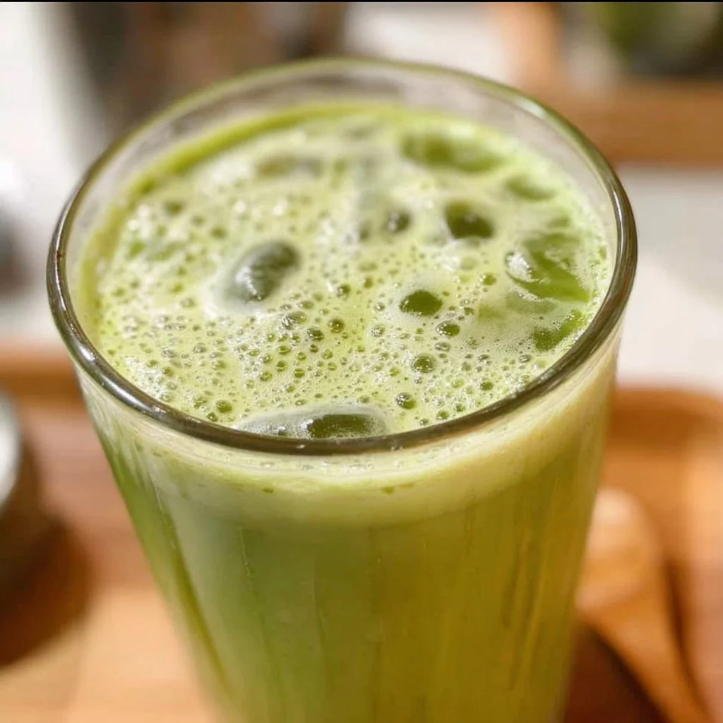 Refreshing iced matcha collagen latte in a glass with a green background