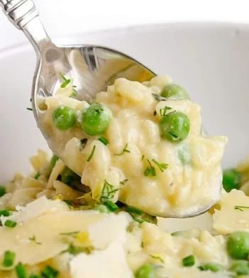 Creamy pea risotto garnished with fresh peas and herbs
