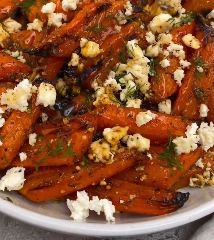 Honey garlic roasted carrots topped with feta cheese on a serving plate