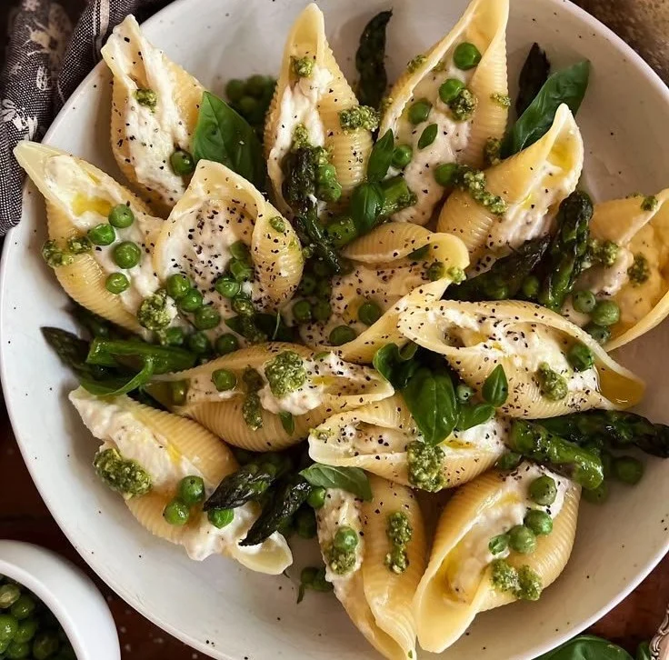 Lemony ricotta stuffed shells with peas and asparagus on a plate