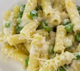 A bowl of pasta with peas and ricotta cheese sprinkled with herbs