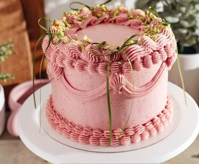Pistachio cake with raspberry jam and buttercream frosting on a decorative plate