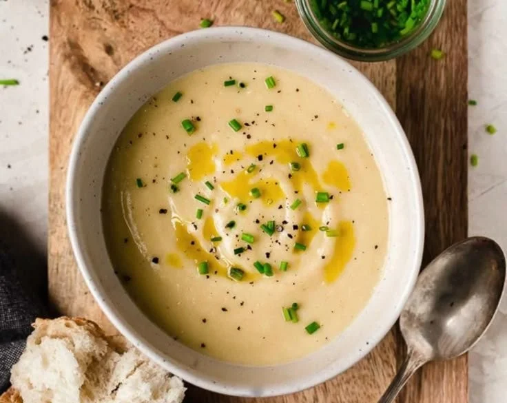A bowl of creamy potato leek soup garnished with fresh herbs