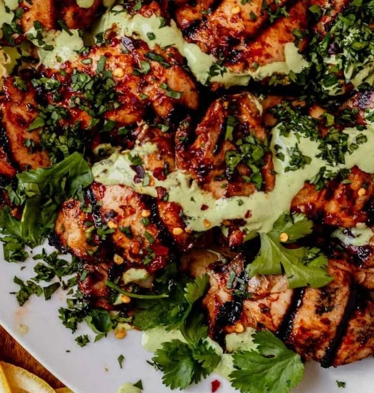 Spicy harissa chicken served with creamy cilantro yogurt sauce on a plate.