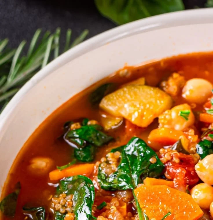 Bowl of hearty meatless quinoa vegetable soup with fresh vegetables and herbs