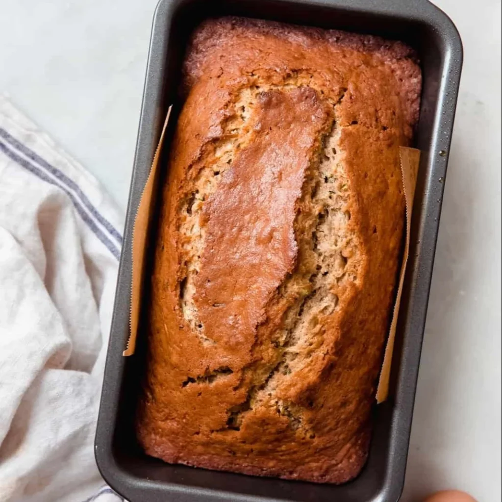 Delicious slice of homemade zucchini bread with fresh zucchini on the side.